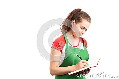 Â Female storekeeper or supermarket employee writing in notebook Stock Photo